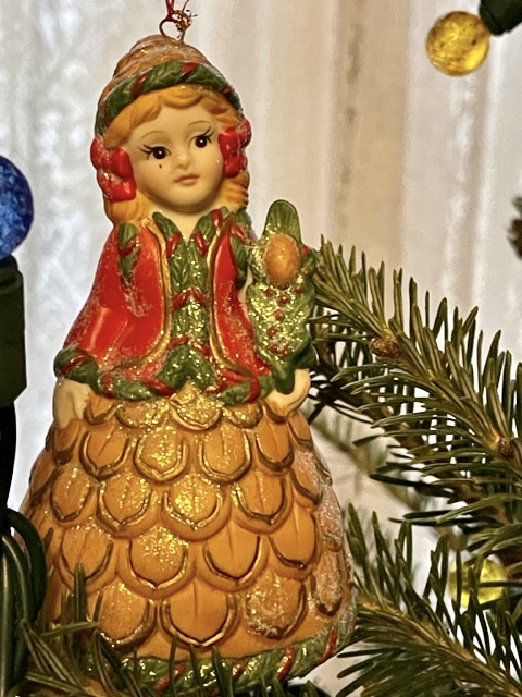 tree ornament - bell shaped like a girl with a hat and braided hair, pine cone like skirt.